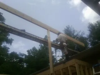 Carpenter setting a ridge beam over a new addition frame — Ice Dam Removal by Roofing Brothers in Elk