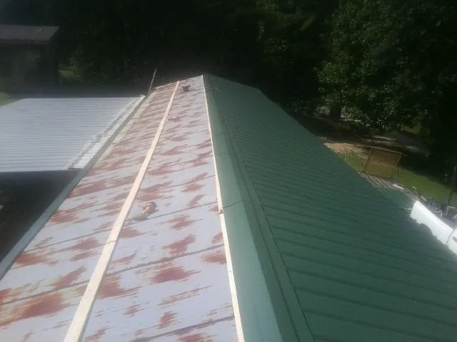 Old rusted panels beside newly installed green metal roofing — Wind Damage Roof Repair by Roofing Brothers in Elk