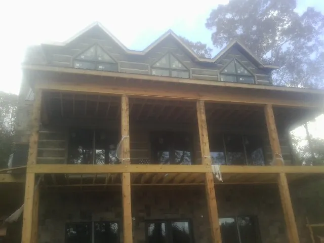 Dormers and porch framing on a large log home under construction — Roof Coating work by our crew in Elk