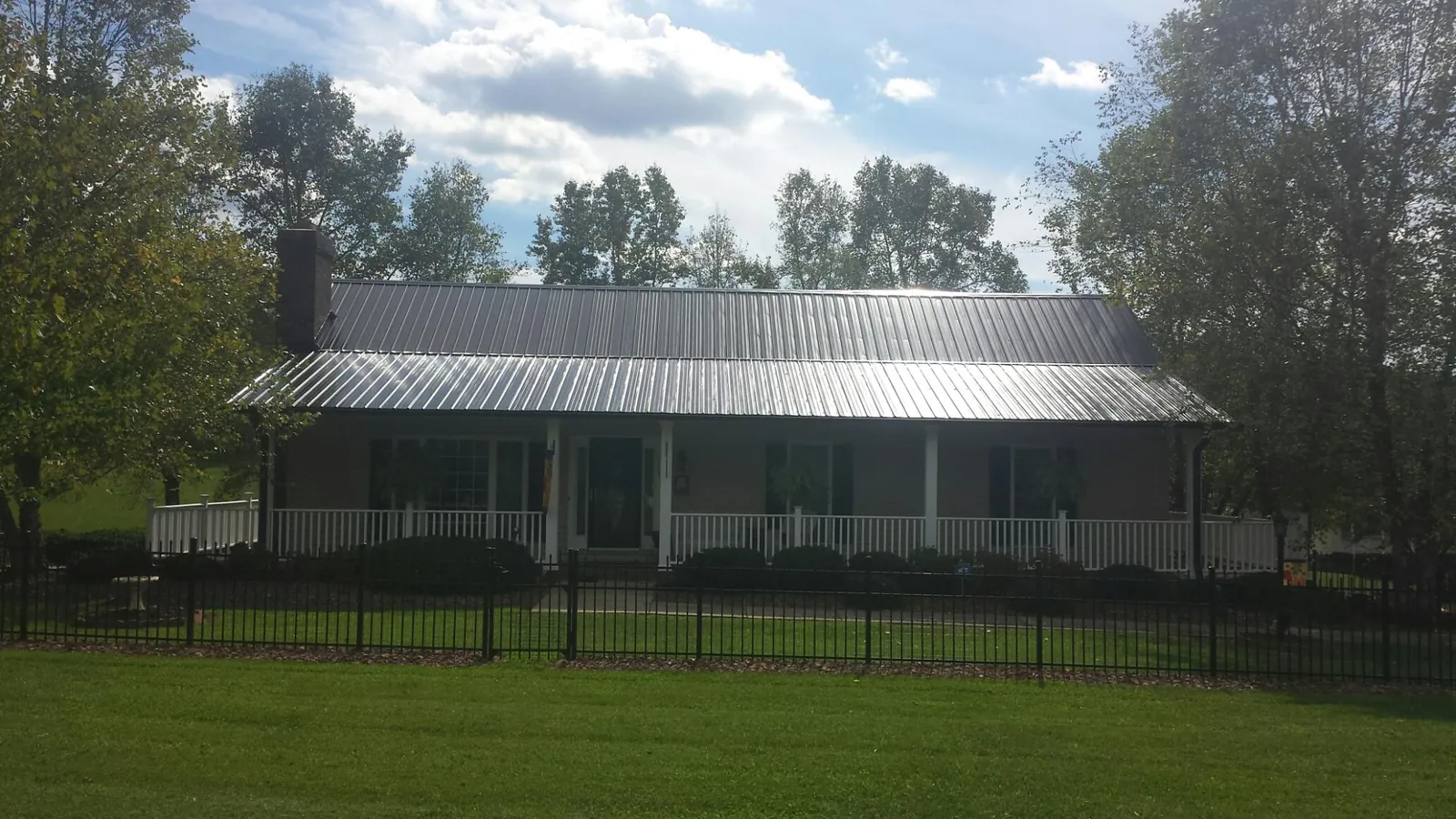 Gray metal roof on a brick ranch with a full width front porch — Gutter Guard Installation work by our crew in Elk
