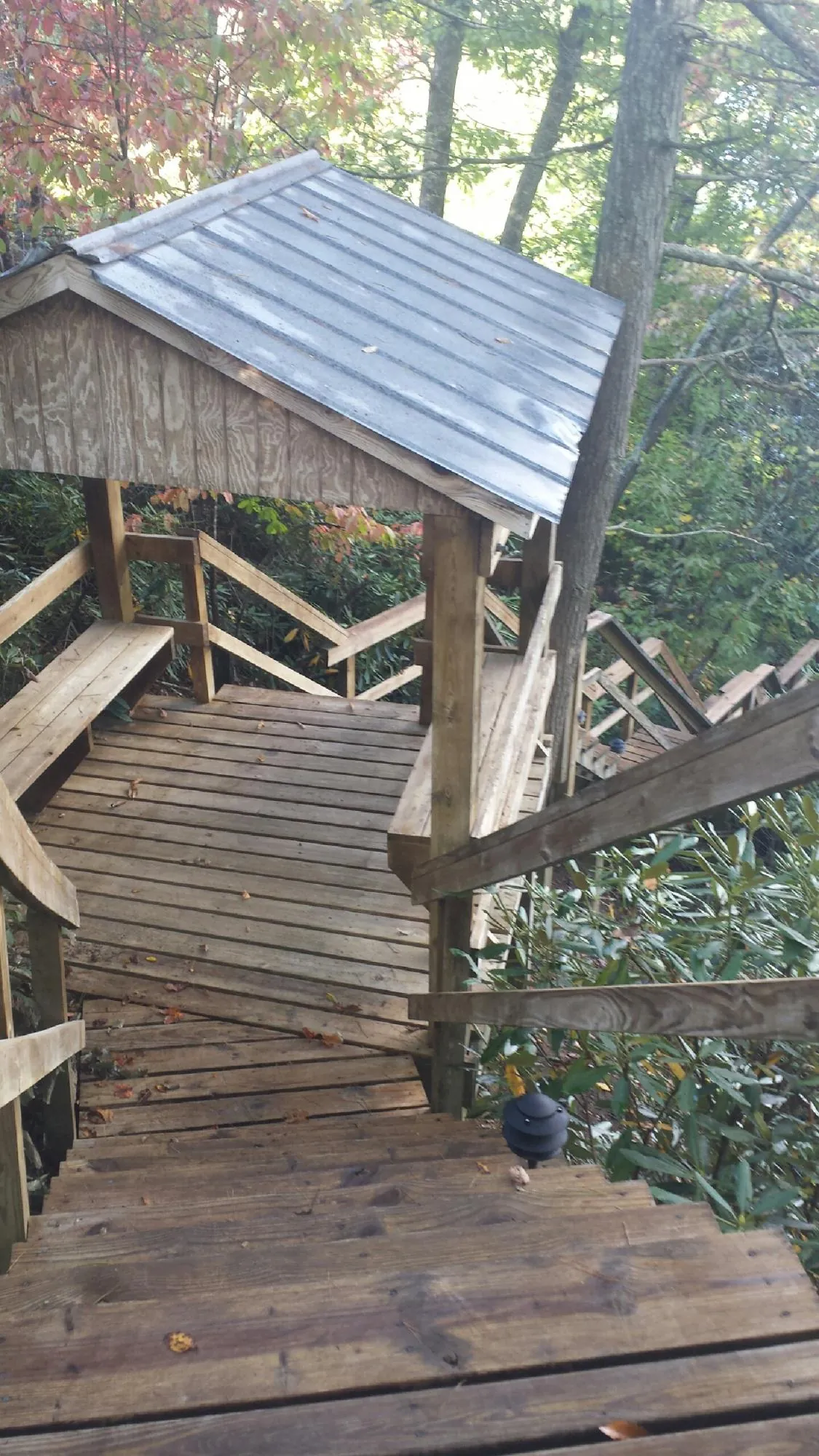 Metal roofed shelter over wooden steps on a wooded walkway — Skylight Repair & Installation work by our crew in Elk