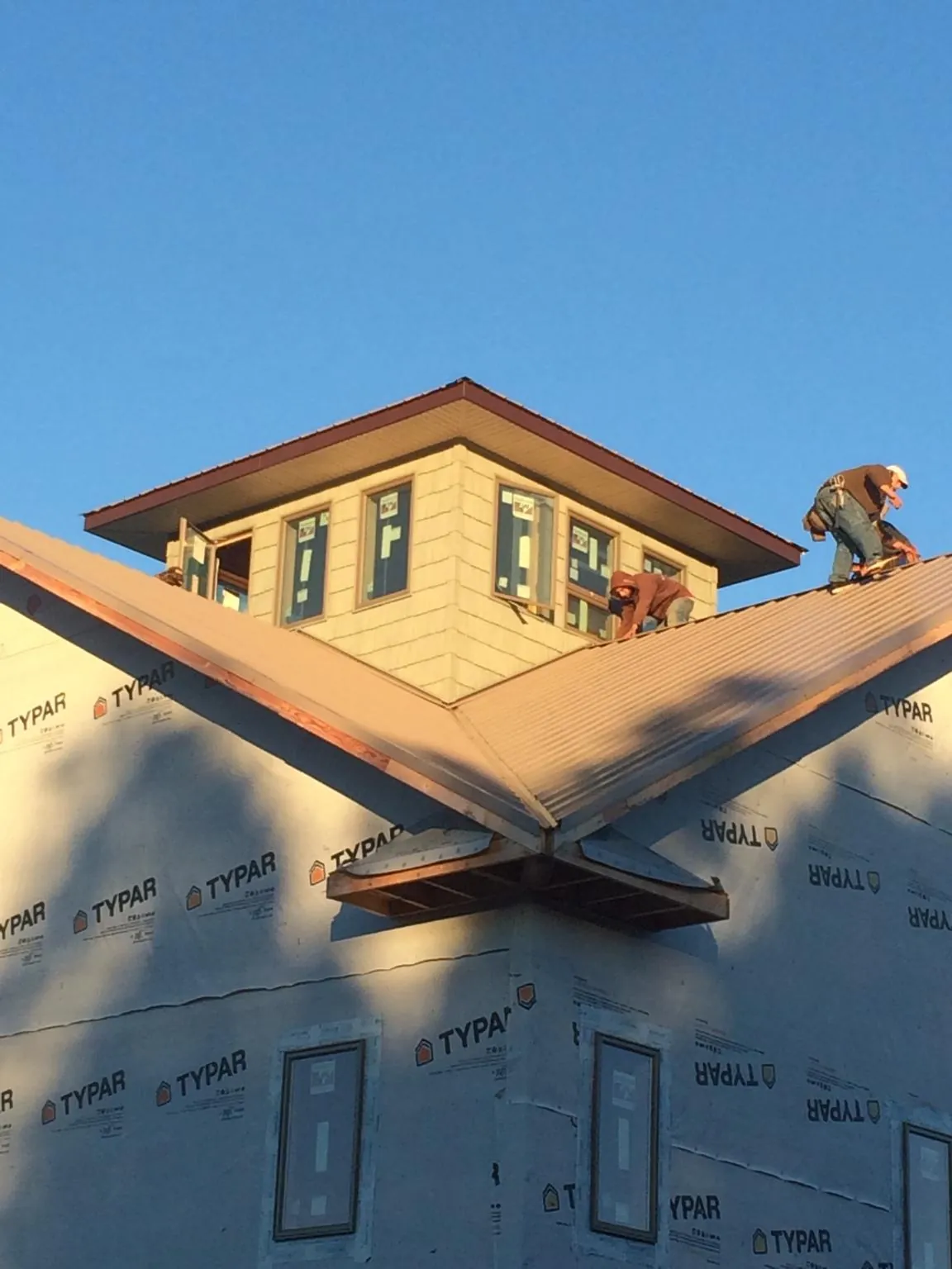 Roofers working around a rooftop cupola on a new metal roof at sunset — Roof Waterproofing in Elk by Roofing Brothers